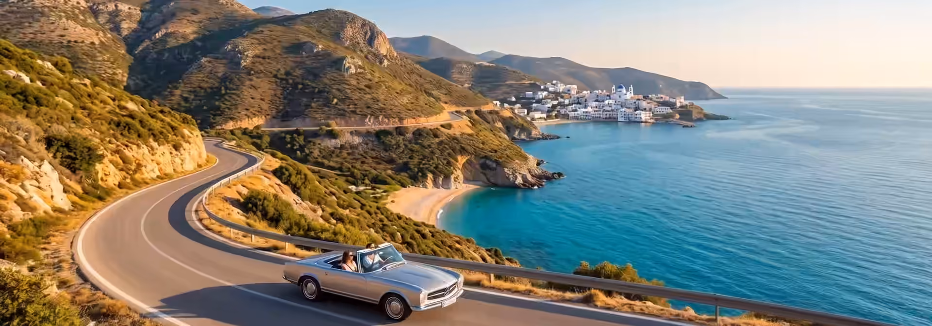 Car traveling on a winding mountain road under a clear blue sky