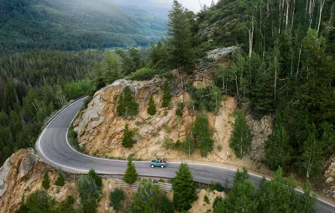 Car traveling on a winding mountain road under a clear blue sky